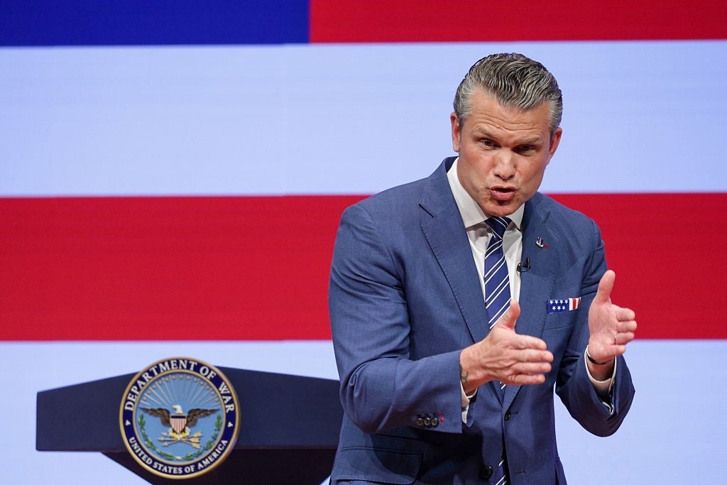 Mann i dress snakker lidenskapelig foran et podium og et stort amerikansk flagg i bakgrunnen