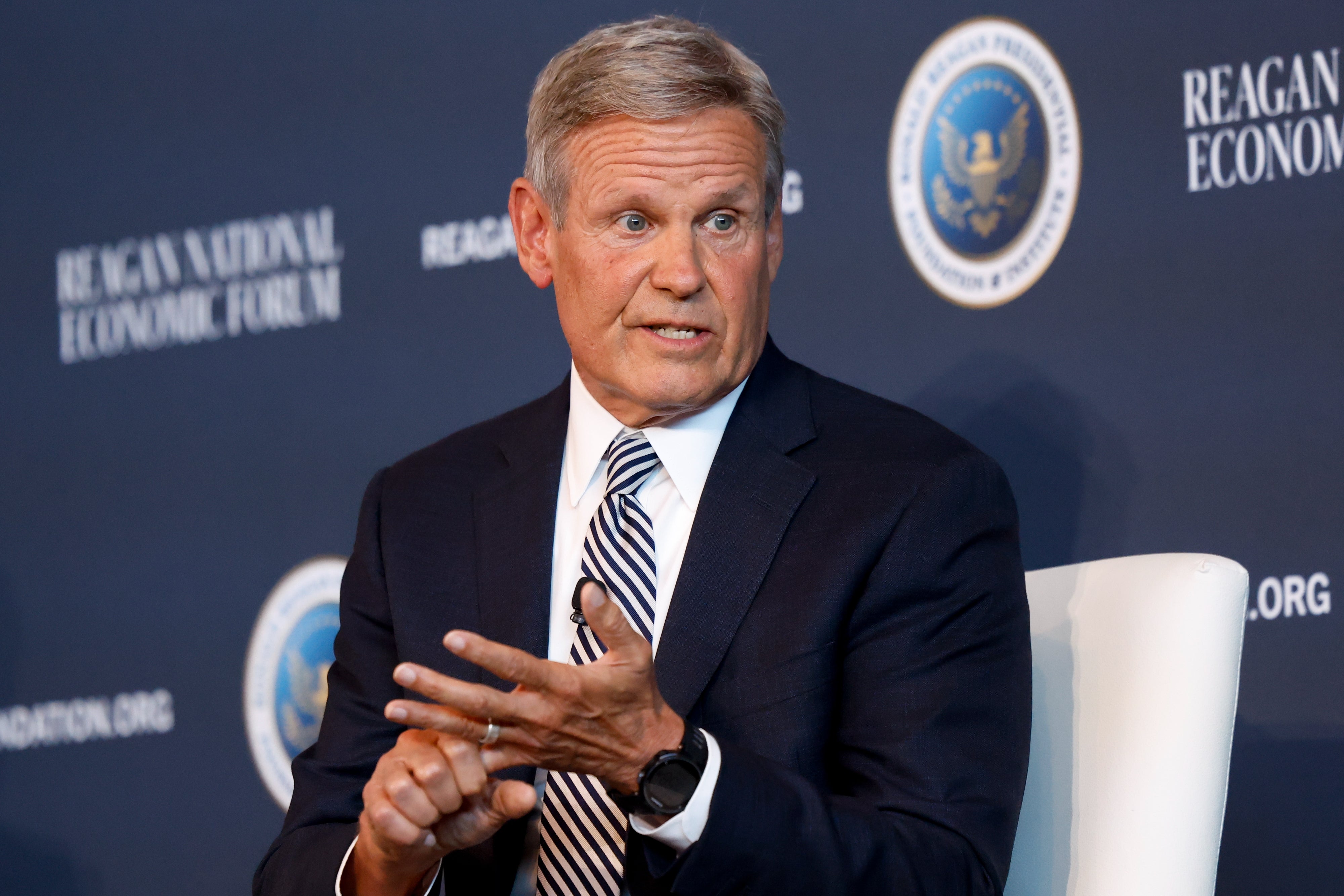 En mann i forretningsdrakt taler på Reagan National Economic Forum og gestikulerer med hendene