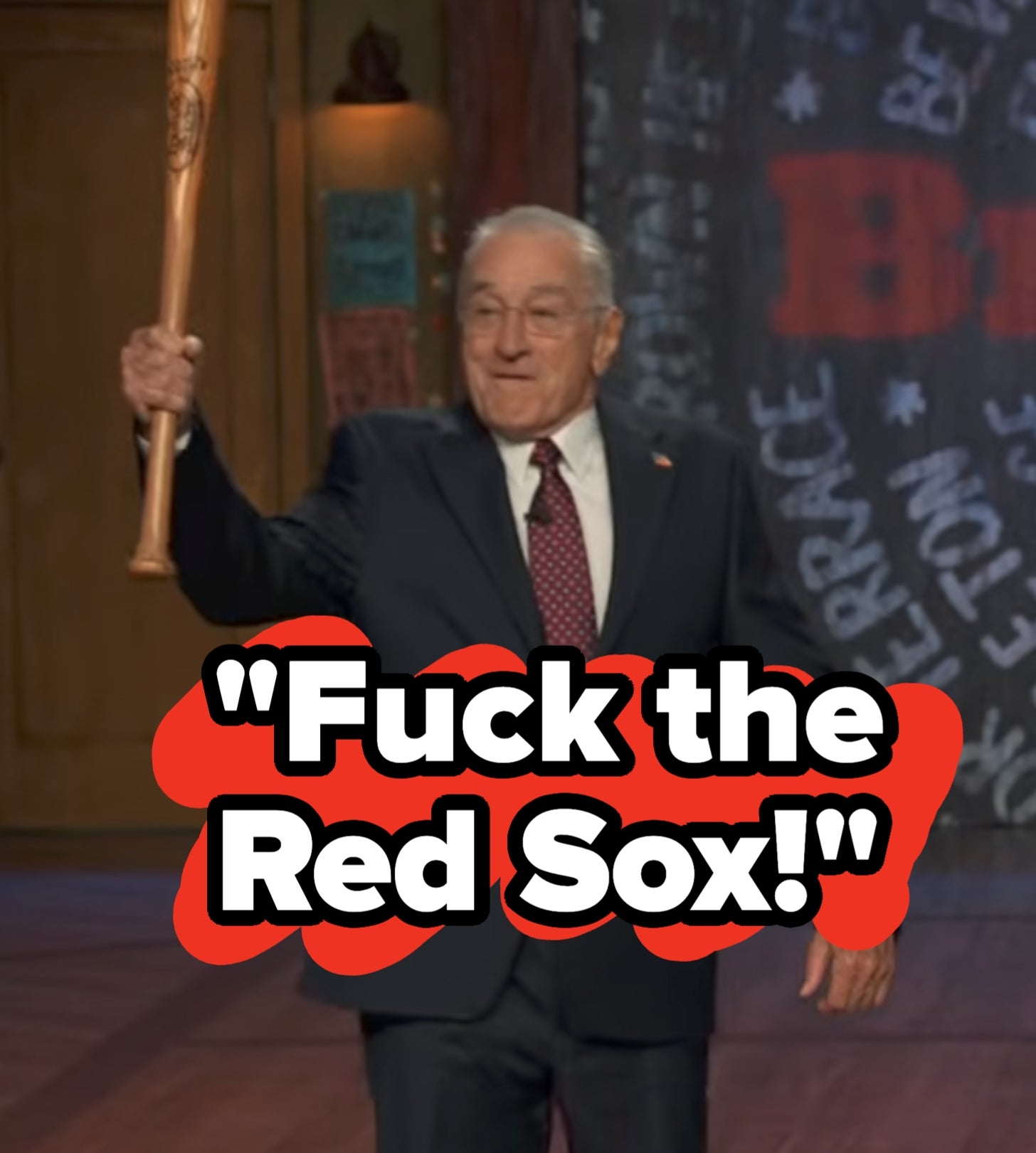 Person i dress som holder et baseballballtre på en scene med et bakteppe av tekst