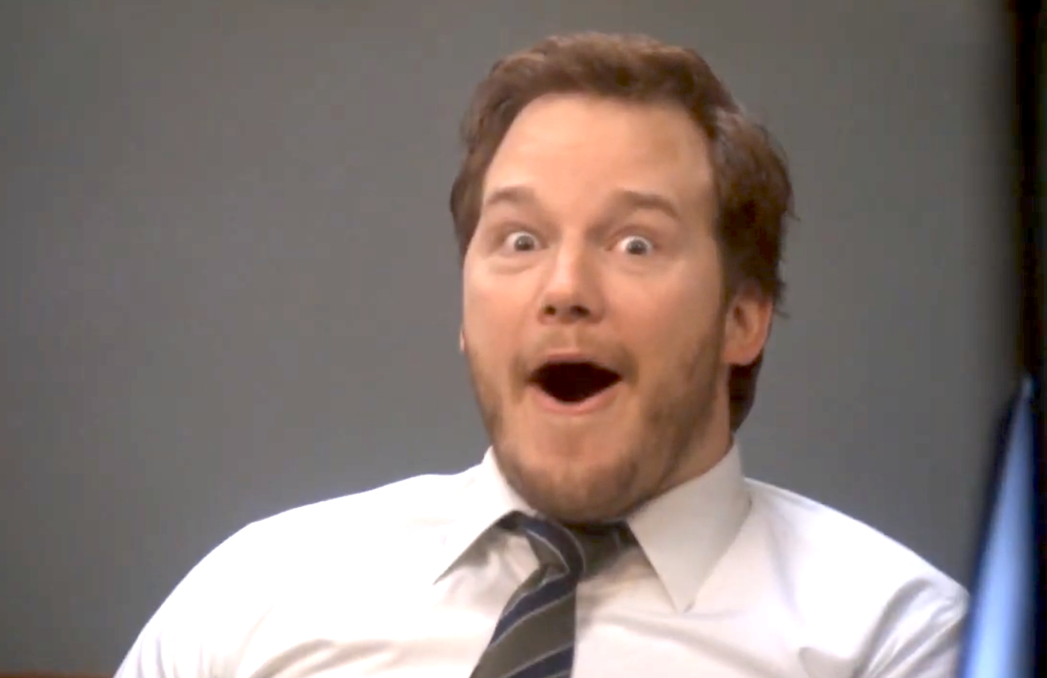 A amazed antheral successful a suit and necktie with a humorous expression, sitting indoors