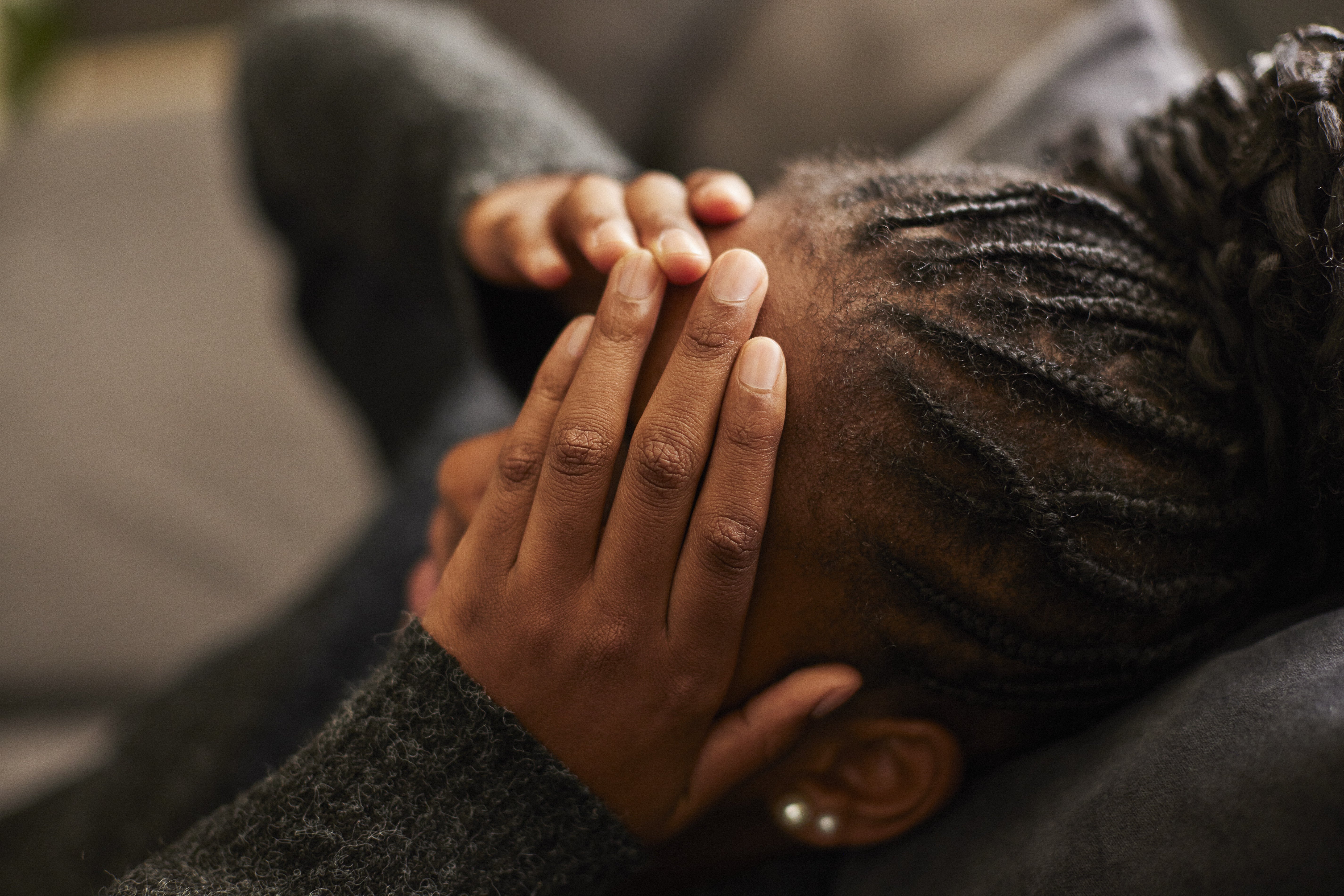 Person lying down with hands covering face, appearing stressed or overwhelmed
