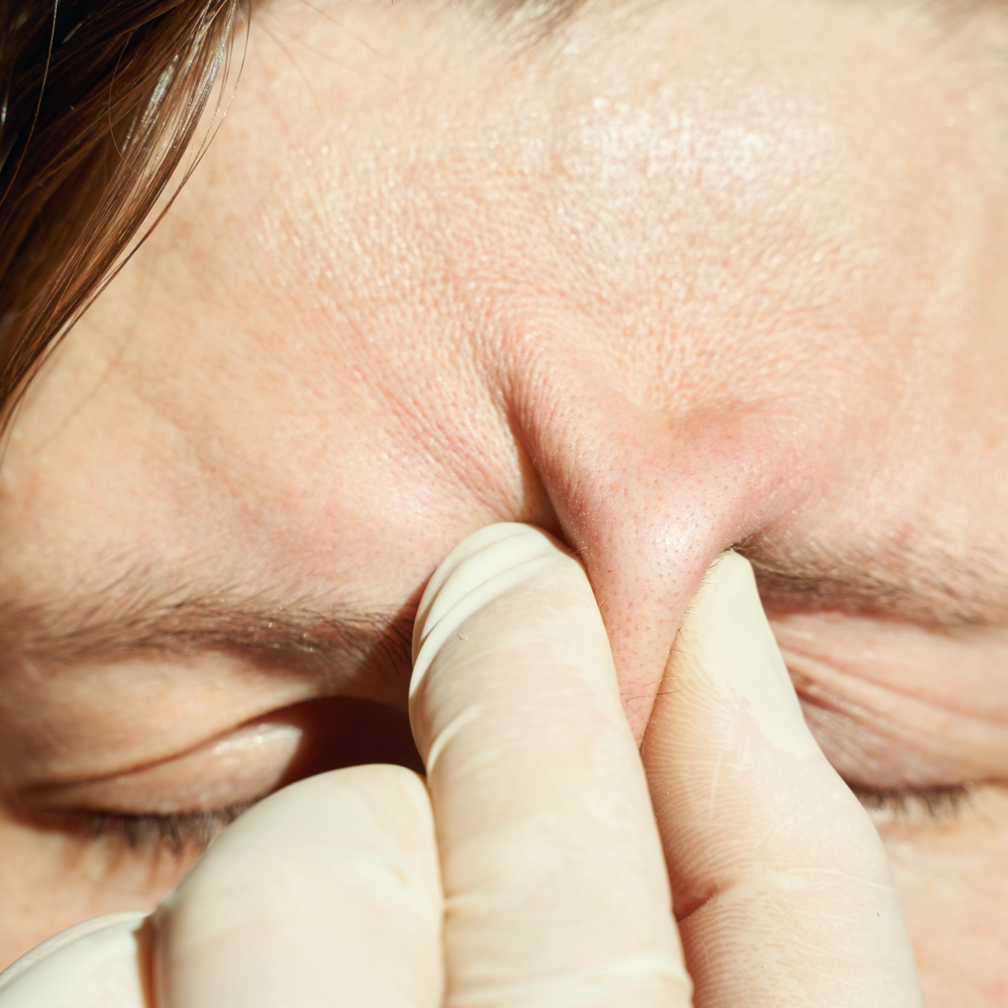 Person squeezing skin between eyebrows, possibly focusing on skincare or stress relief practice