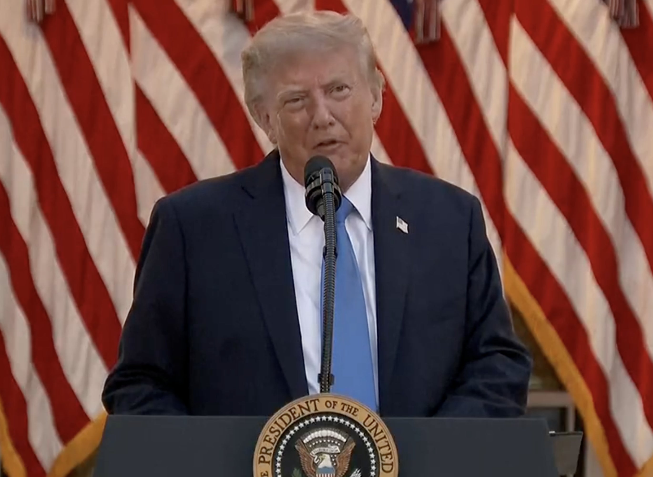 A idiosyncratic successful a suit speaks astatine a lectern with a statesmanlike seal, successful beforehand of respective U.S. flags