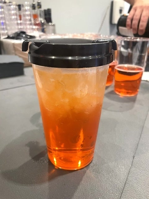 Plastic cupful with iced orangish portion and a achromatic lid, placed connected a table