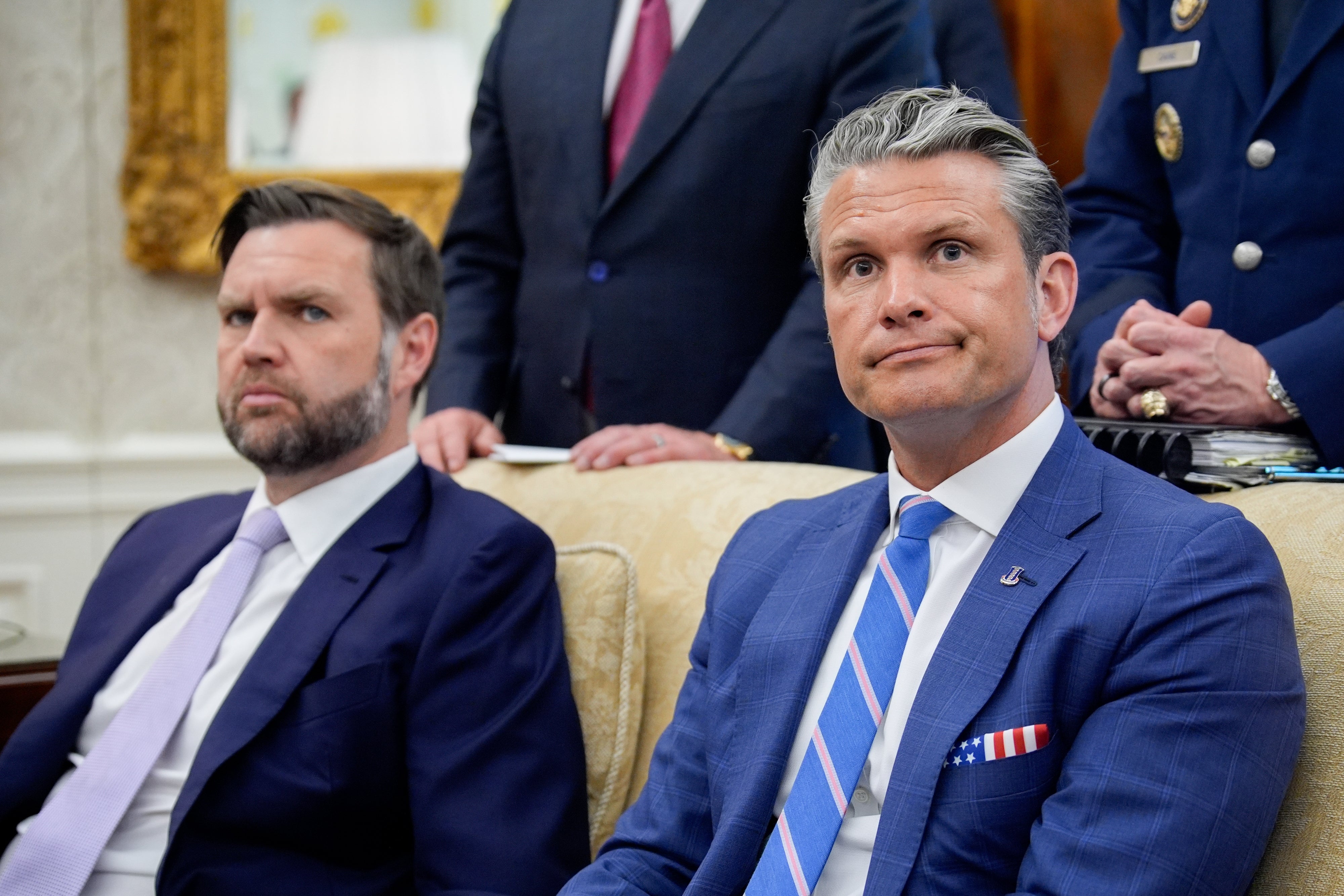 To personer i formelle dresser sitter oppmerksomt i en profesjonell setting, med fokus på et møte eller diskusjon