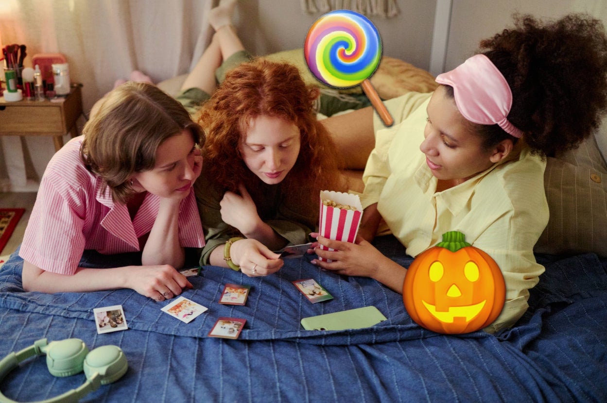 Three people on a bed play a card game, surrounded by festive Halloween and candy-themed decorations