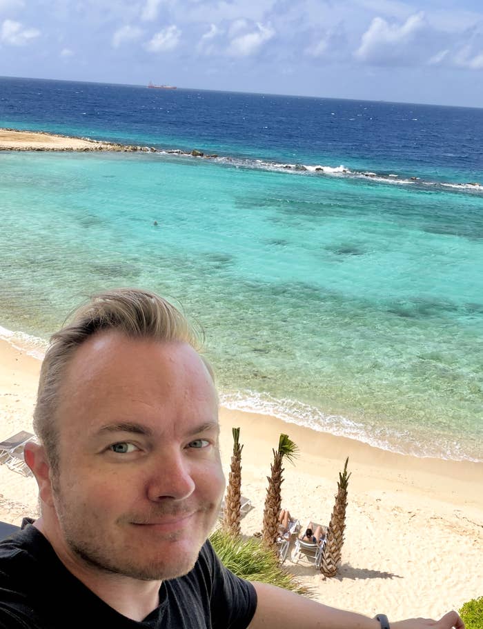 Person taking a selfie connected  a formation  with wide   bluish  h2o  and a sandy enactment     successful  the background