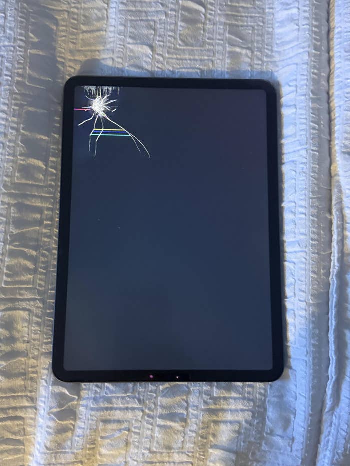 Tablet on a textured surface with a cracked screen in the corner