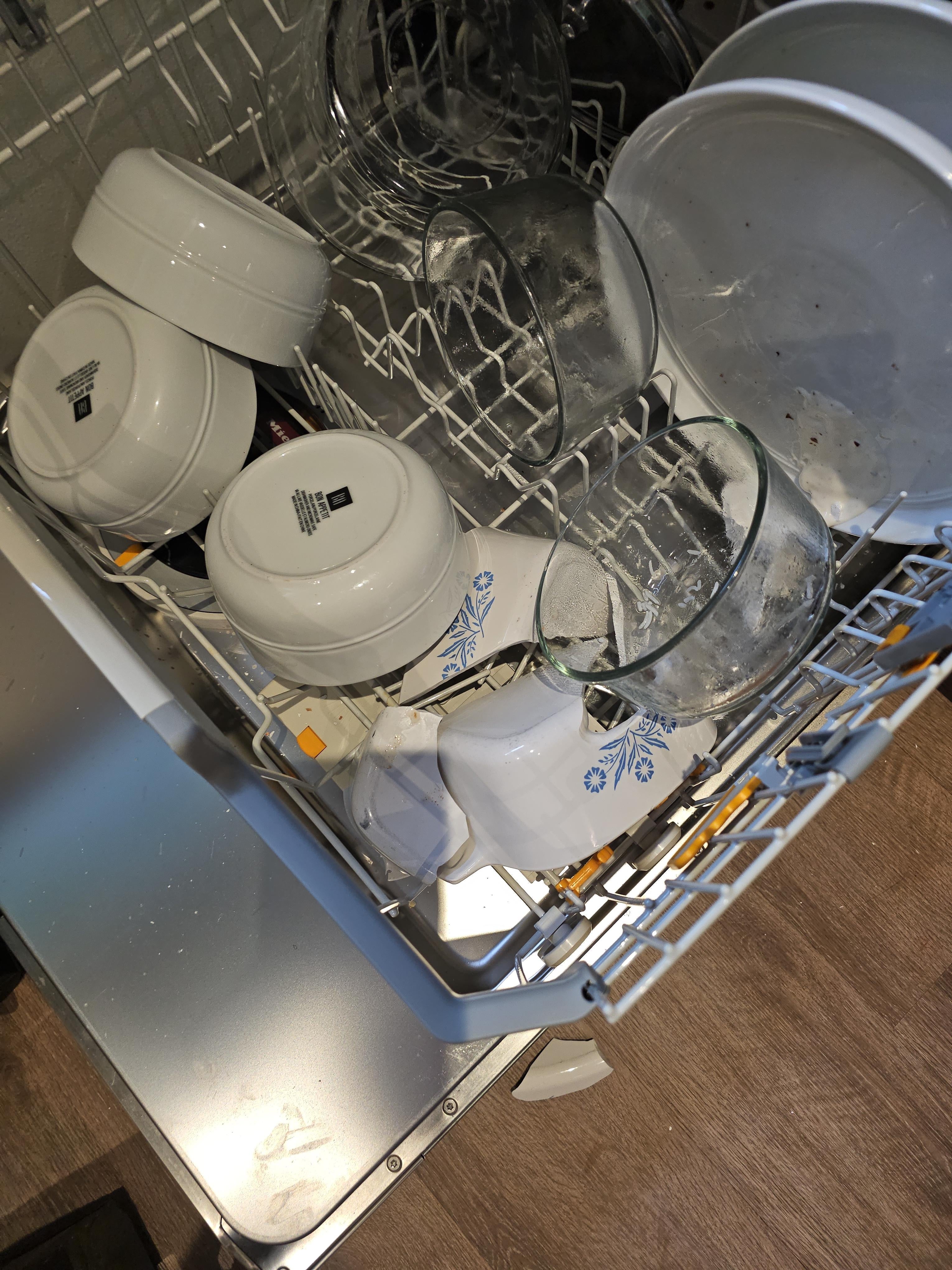 Open dishwasher with various bowls and glasses arranged inside