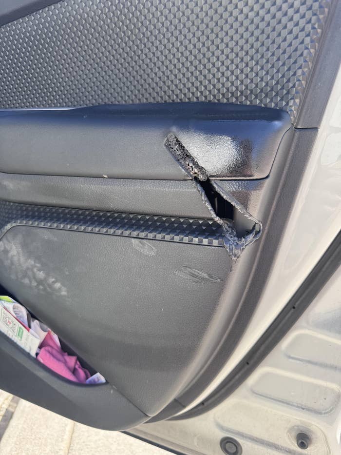 Car door interior with a tear in the armrest, exposing foam