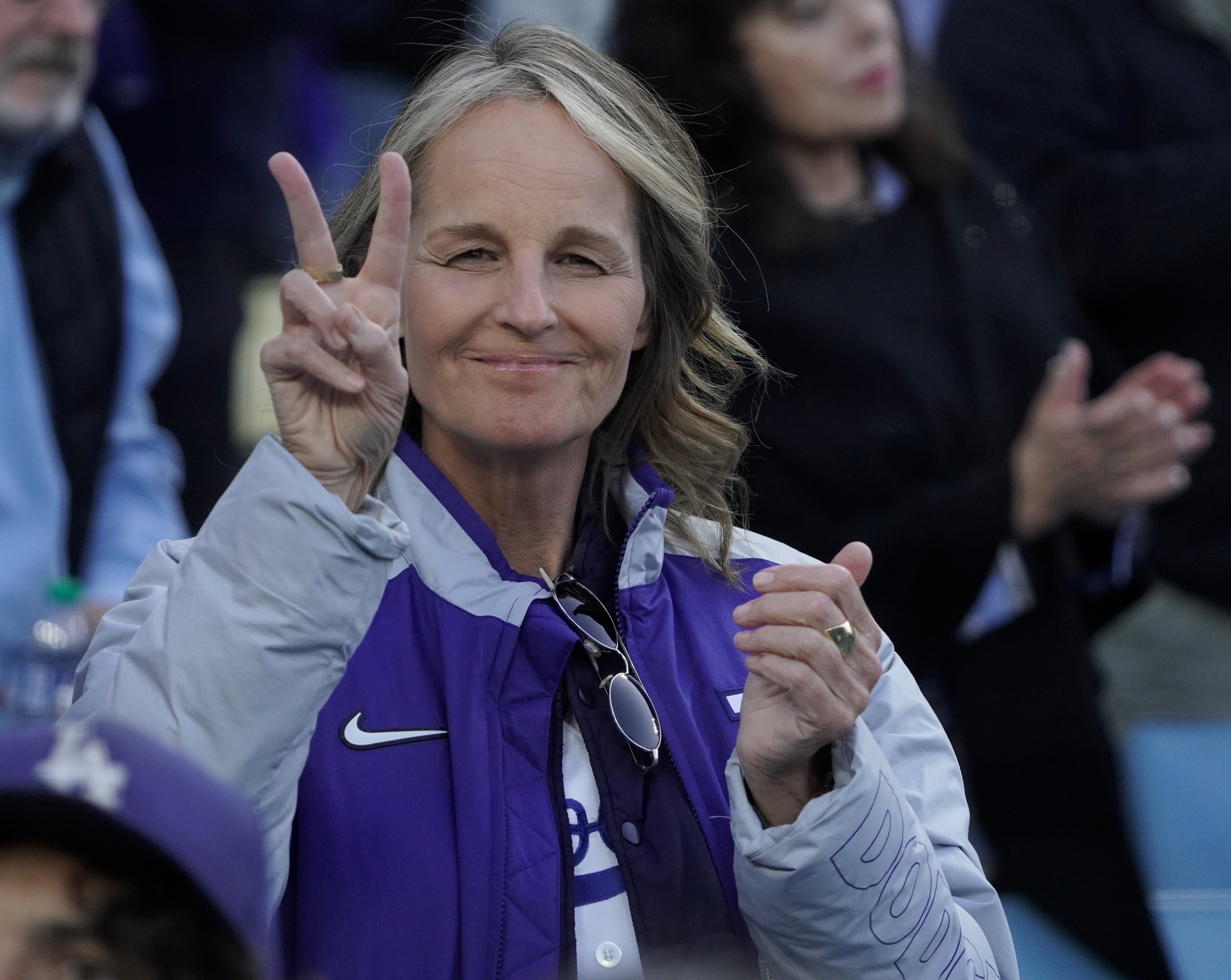 Helen Hunt smiling, making a peace sign, and wearing a casual jacket at a public event