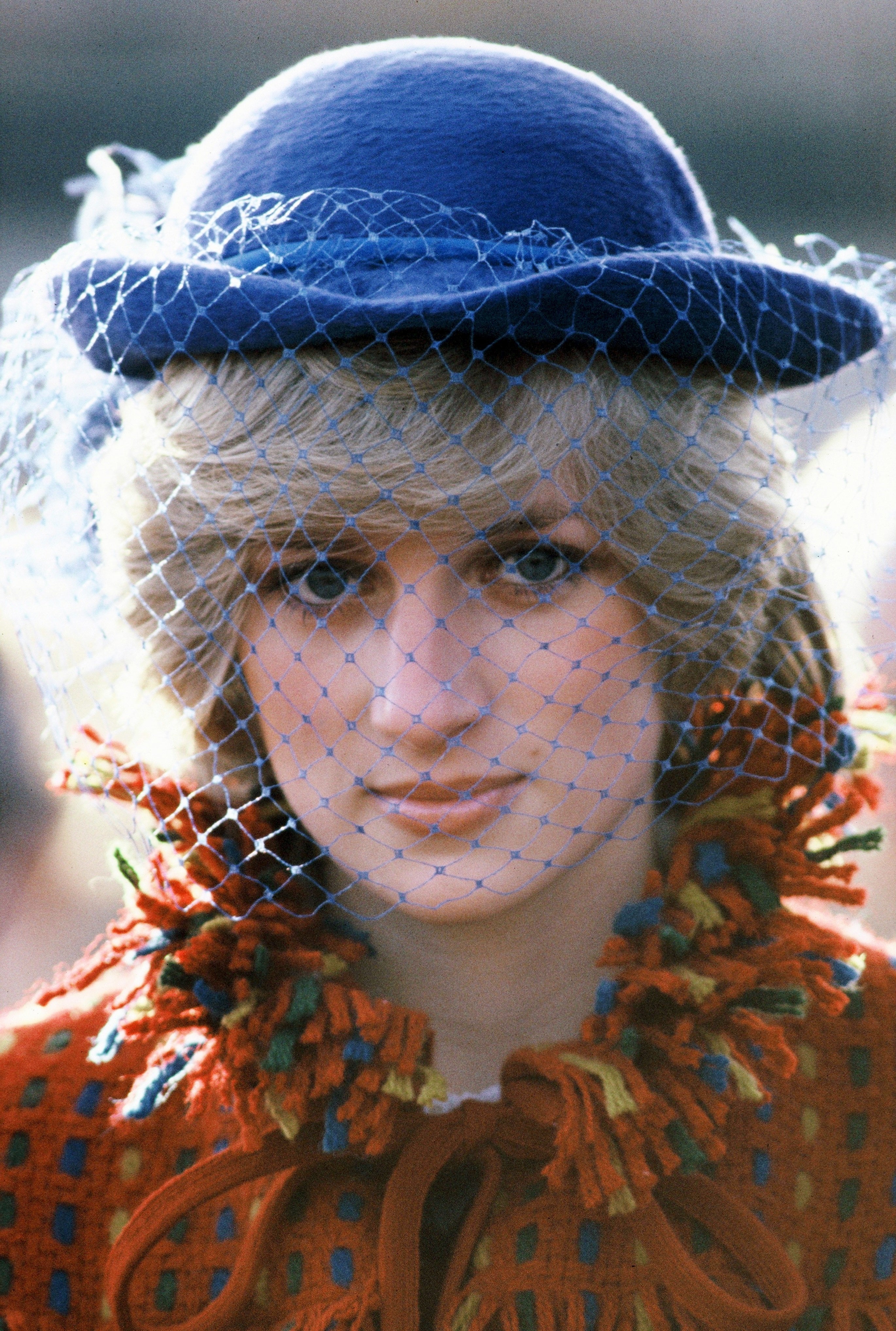 Princess Diana wearing a red patterned coat and blue hat with a vintage veil