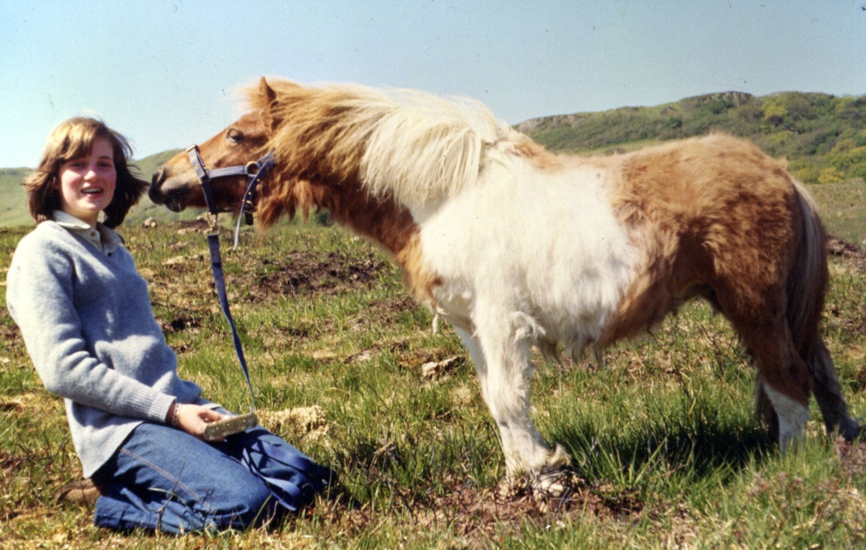 Lady Diana Spencer posing with a pony in a grassy field