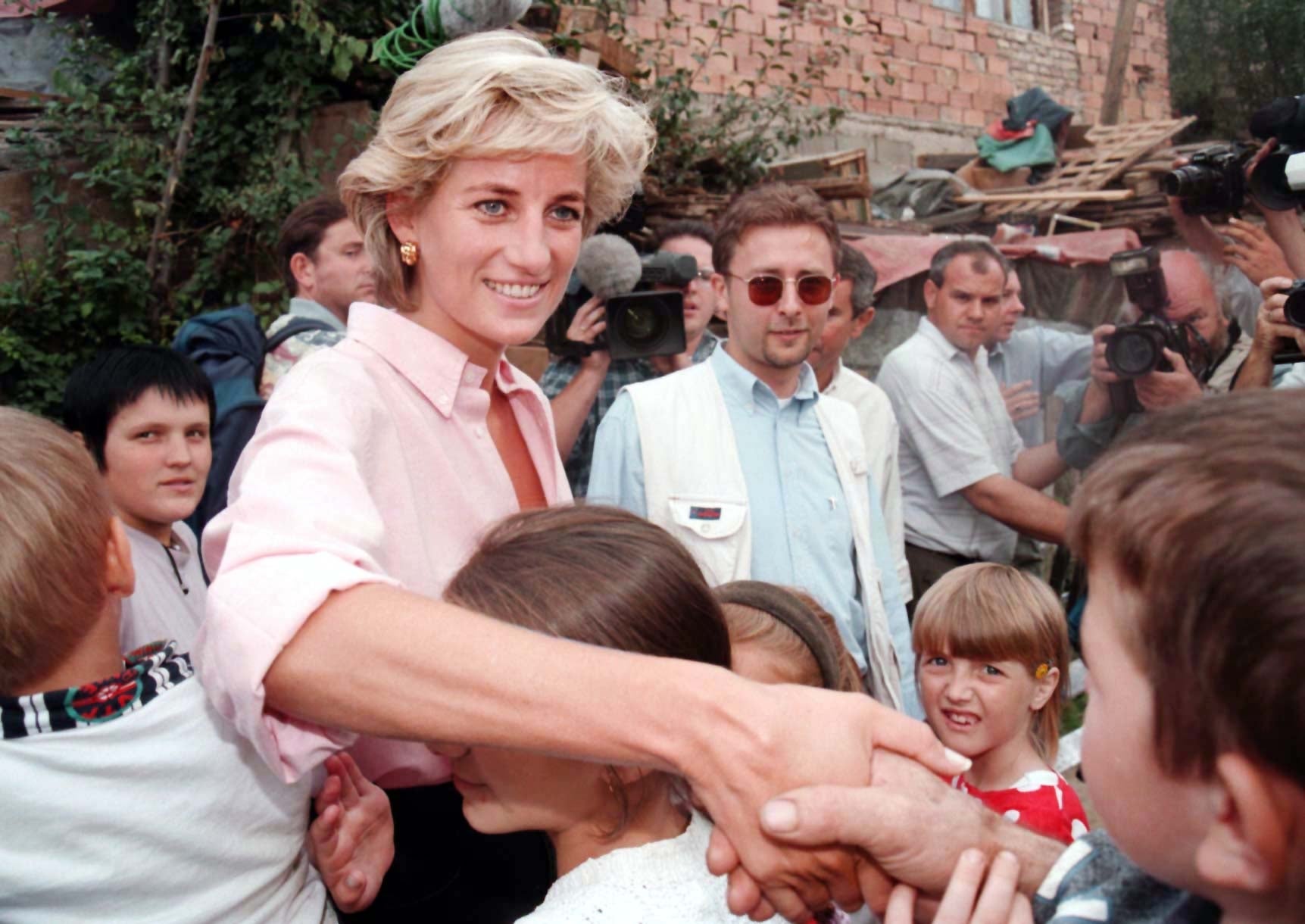 Princess Diana shaking hands, surrounded by children in Bosnia