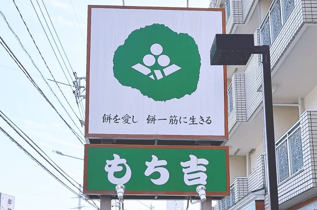 「餅を愛し 餅一筋に生きる」と書かれた看板。店舗「もち吉」前。