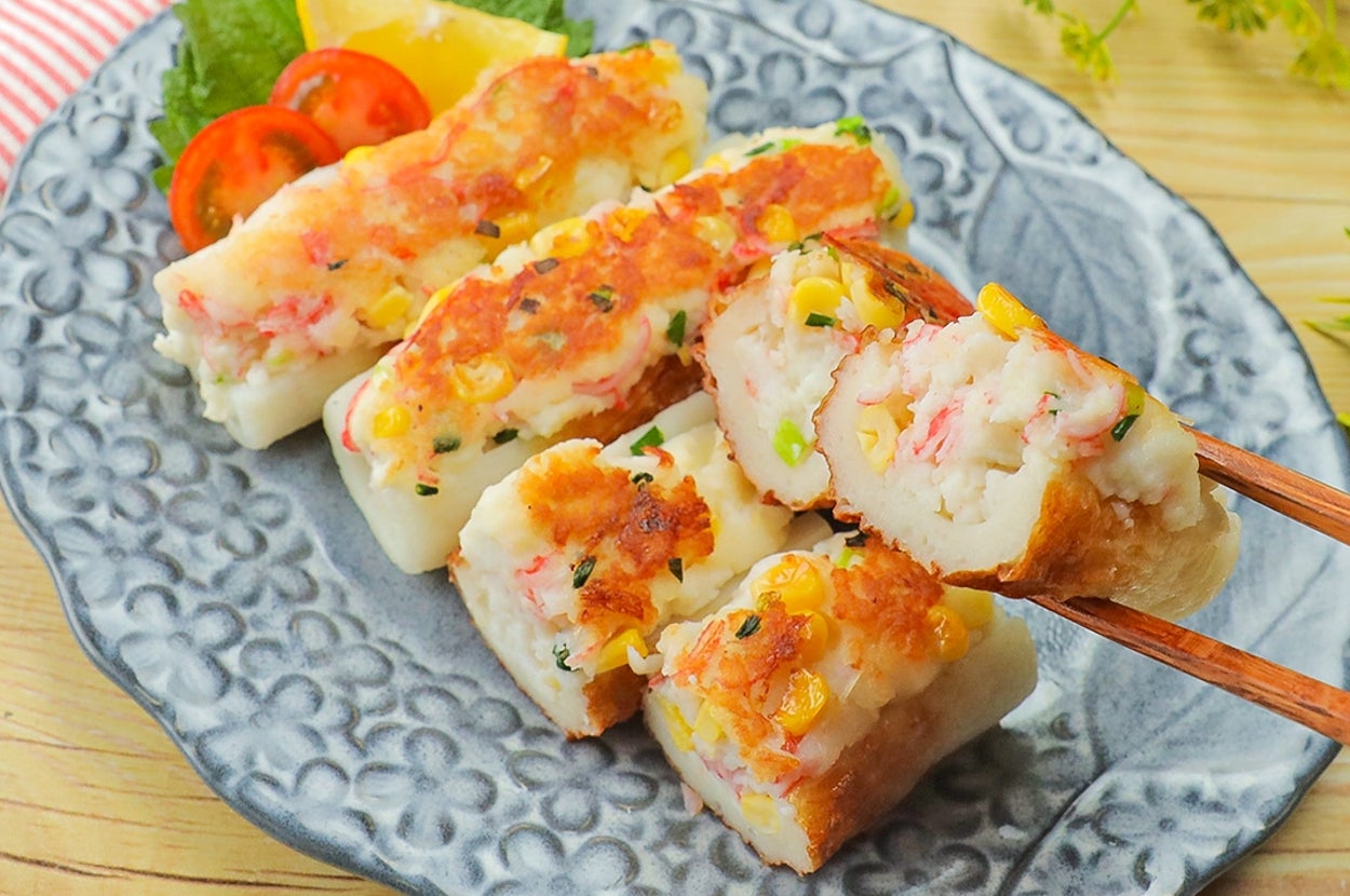 皿に盛られた焼きおにぎりの盛り合わせ。横にトマトやレモン、赤貝、葉が飾られている。