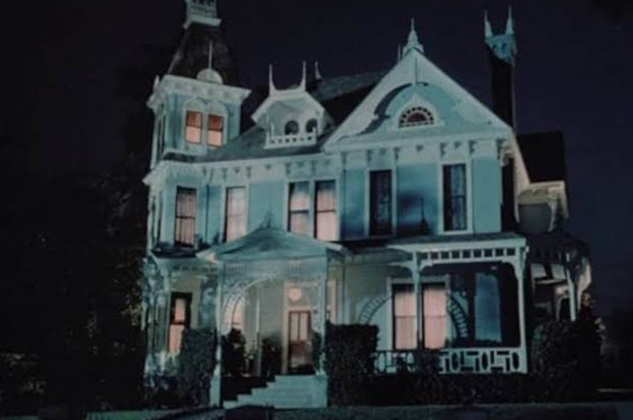 Victorian-style house at night, illuminated with a few windows glowing