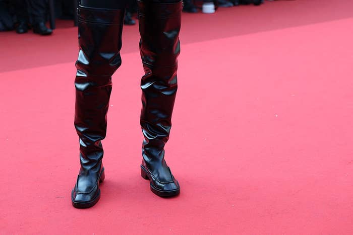 Person wearing shiny leather pants and boots on a red carpet