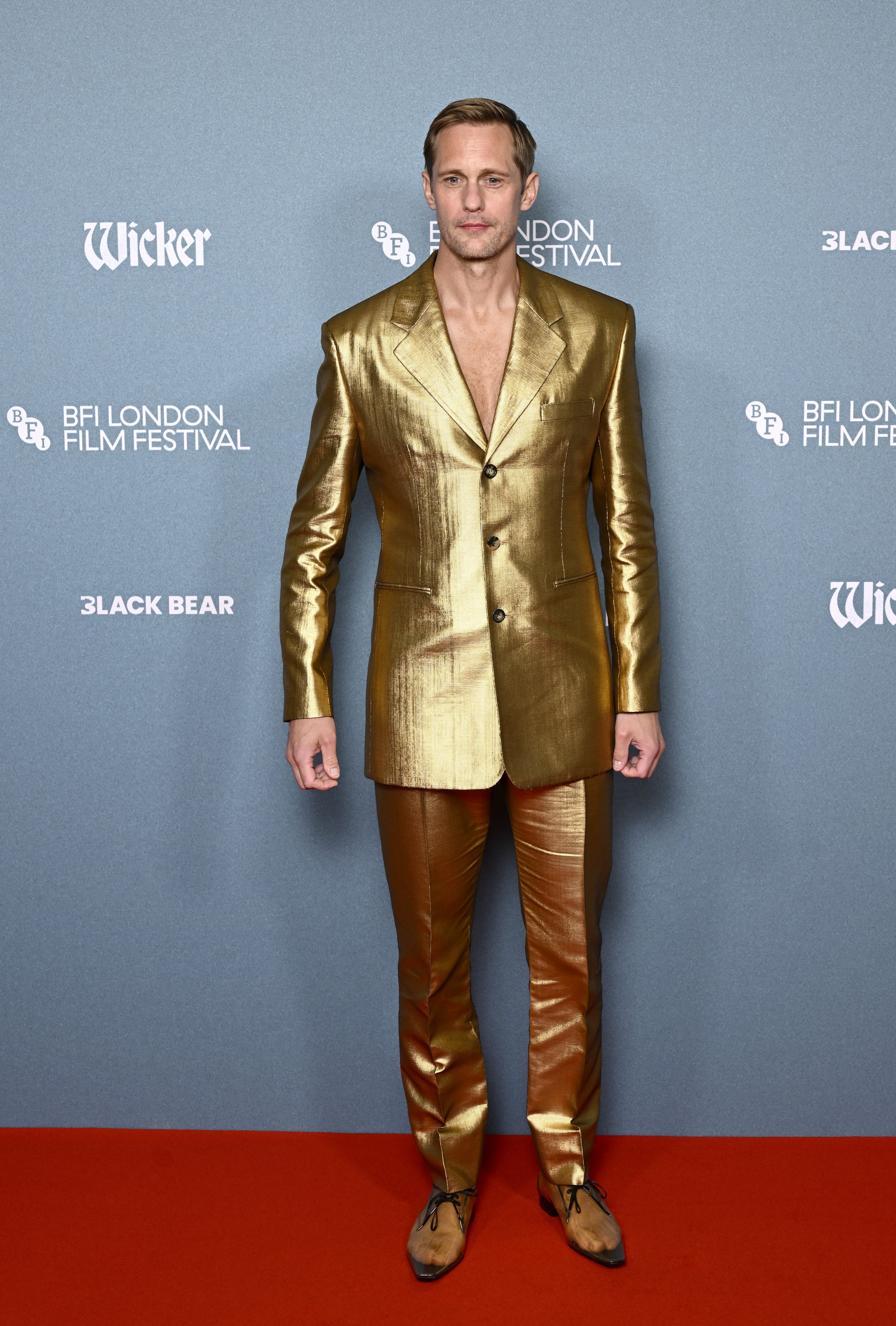 Person in a sleek, metallic suit stands on a red carpet at the BFI London Film Festival
