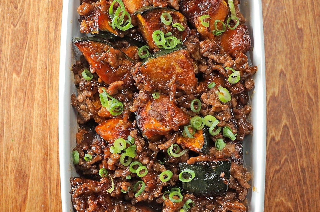 かぼちゃとひき肉の炒め物が白い皿に盛られ、ねぎがトッピングされています。