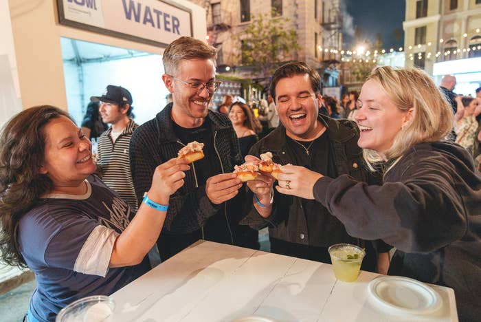 Four radical   stock  a joyful moment, clinking slices of pizza unneurotic  astatine  an outdoor event, with drinks connected  the table