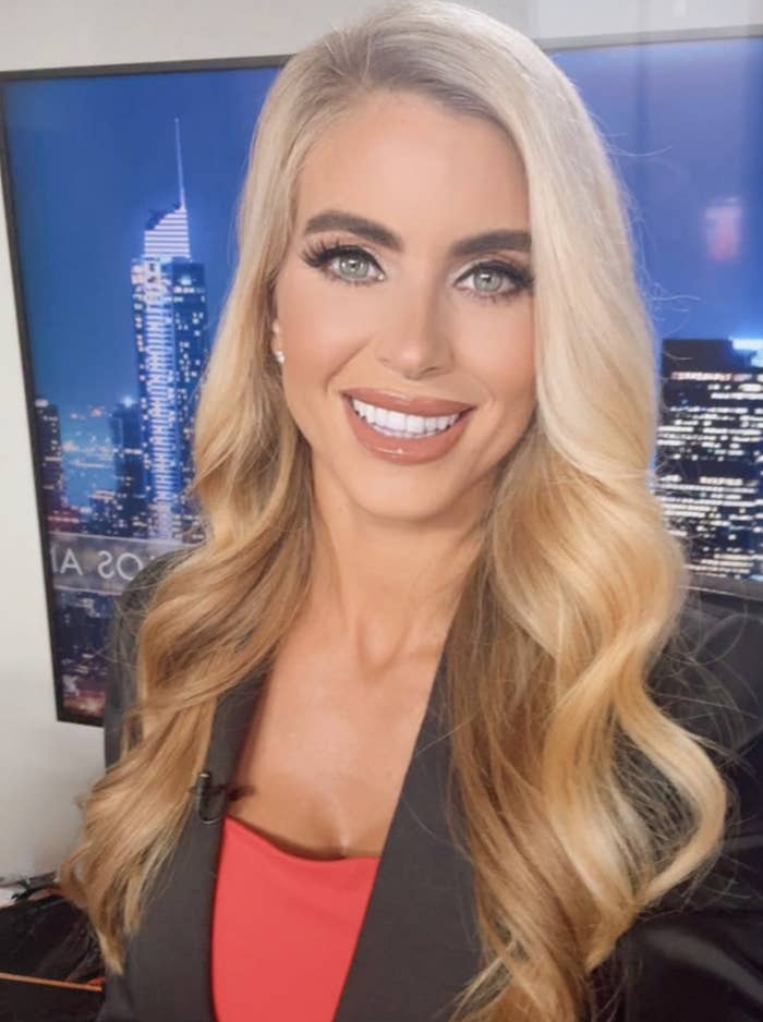 Person smiling successful  a workplace  setting, wearing a blazer with a apical  underneath. City skyline backdrop connected  screen