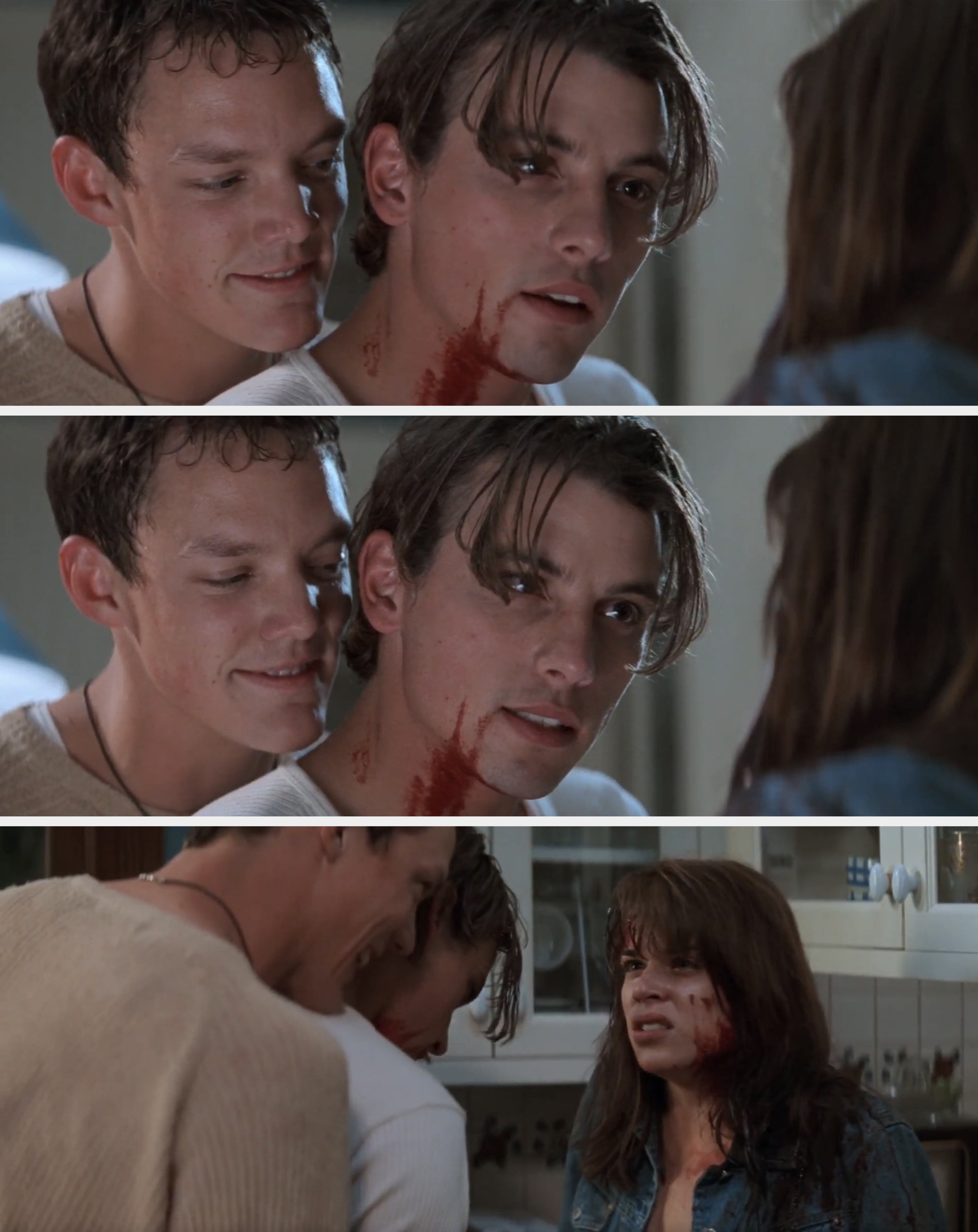 Two men from a movie scene; one with a slight smile, the other with a serious expression and fake blood on his neck, looking at a person off-screen