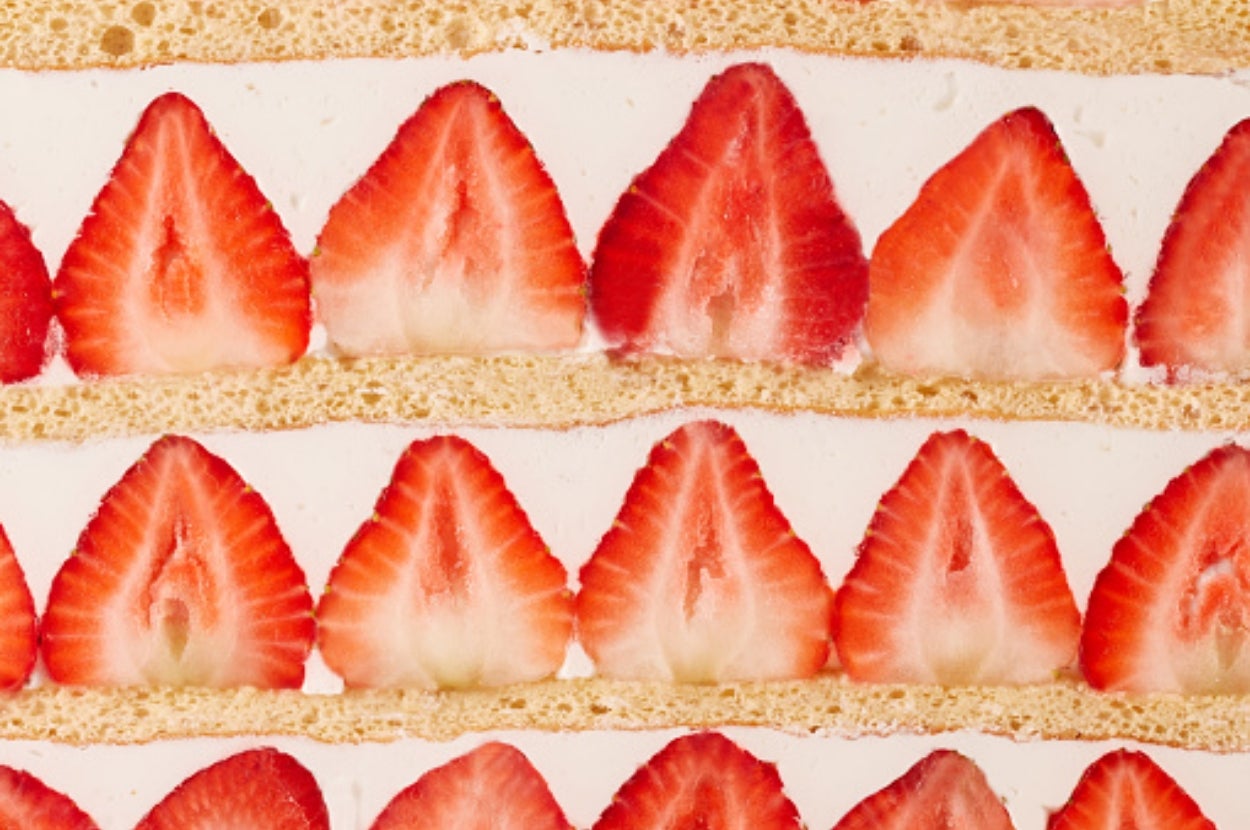 Alternating layers of sliced strawberries and sponge cake with cream, creating a pattern