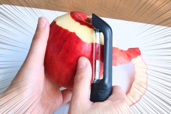 リンゴをピーラーで皮むきしている手元。スピード線で動きを示唆。