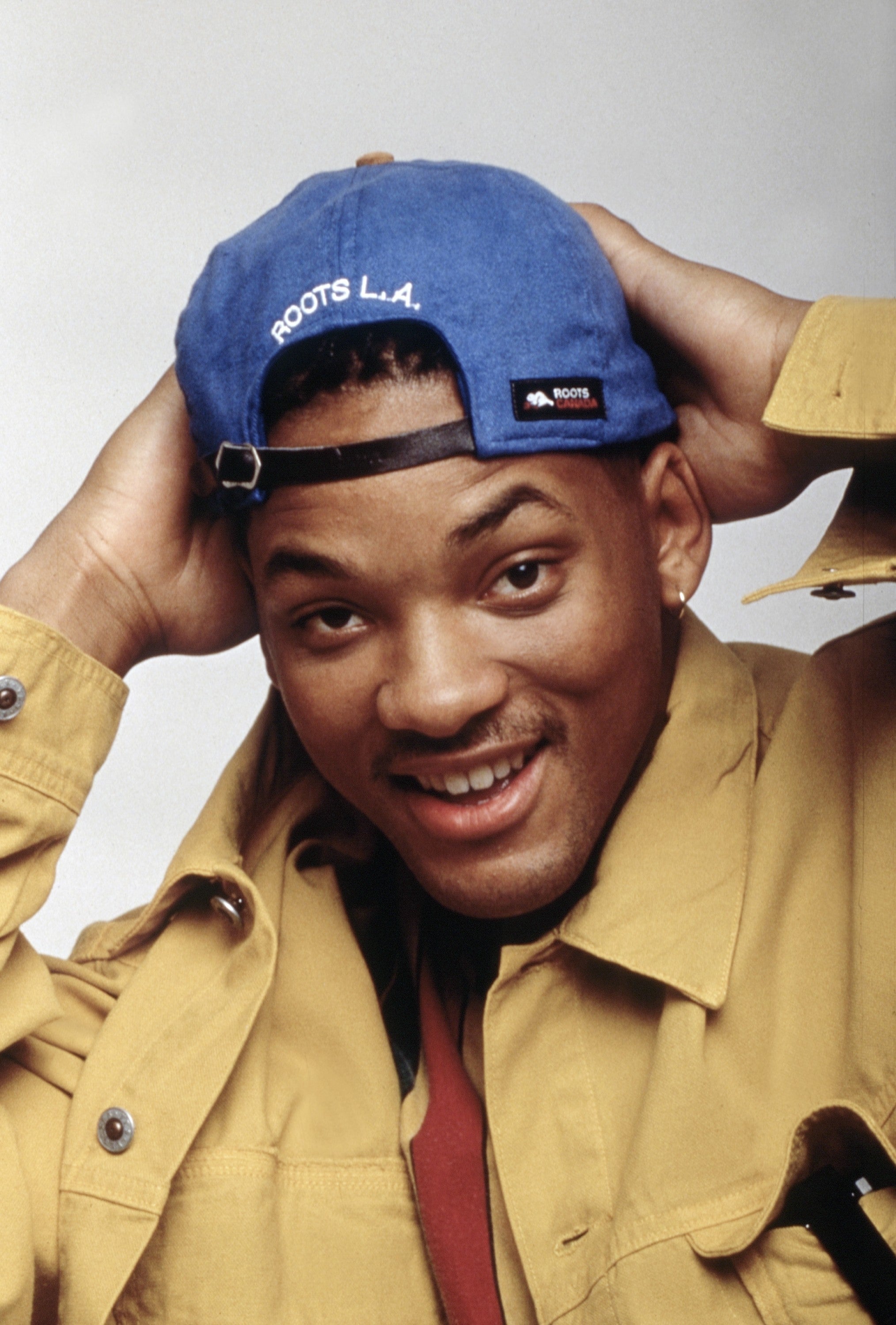 A person smiling, wearing a backward cap, and a casual jacket