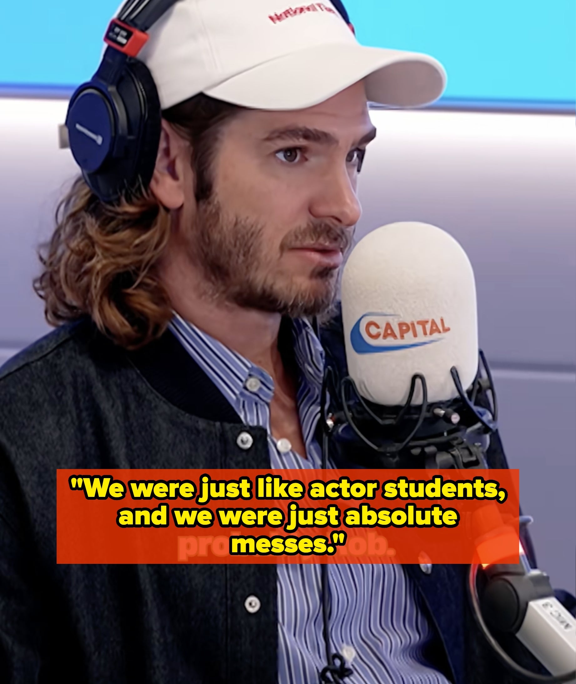 Person with long hair and beard wearing headphones, cap, and jacket, speaking into a microphone in a radio studio. Text reads "probably Rob"
