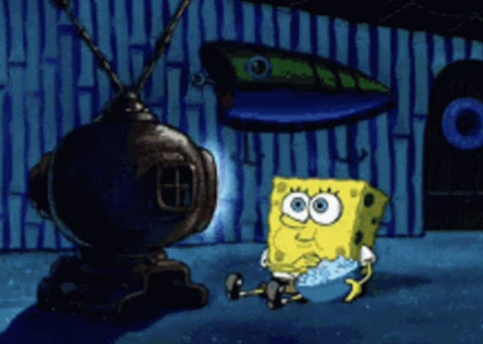 SpongeBob SquarePants watches TV with a bowl of popcorn, sitting on the floor in a nautical-themed room