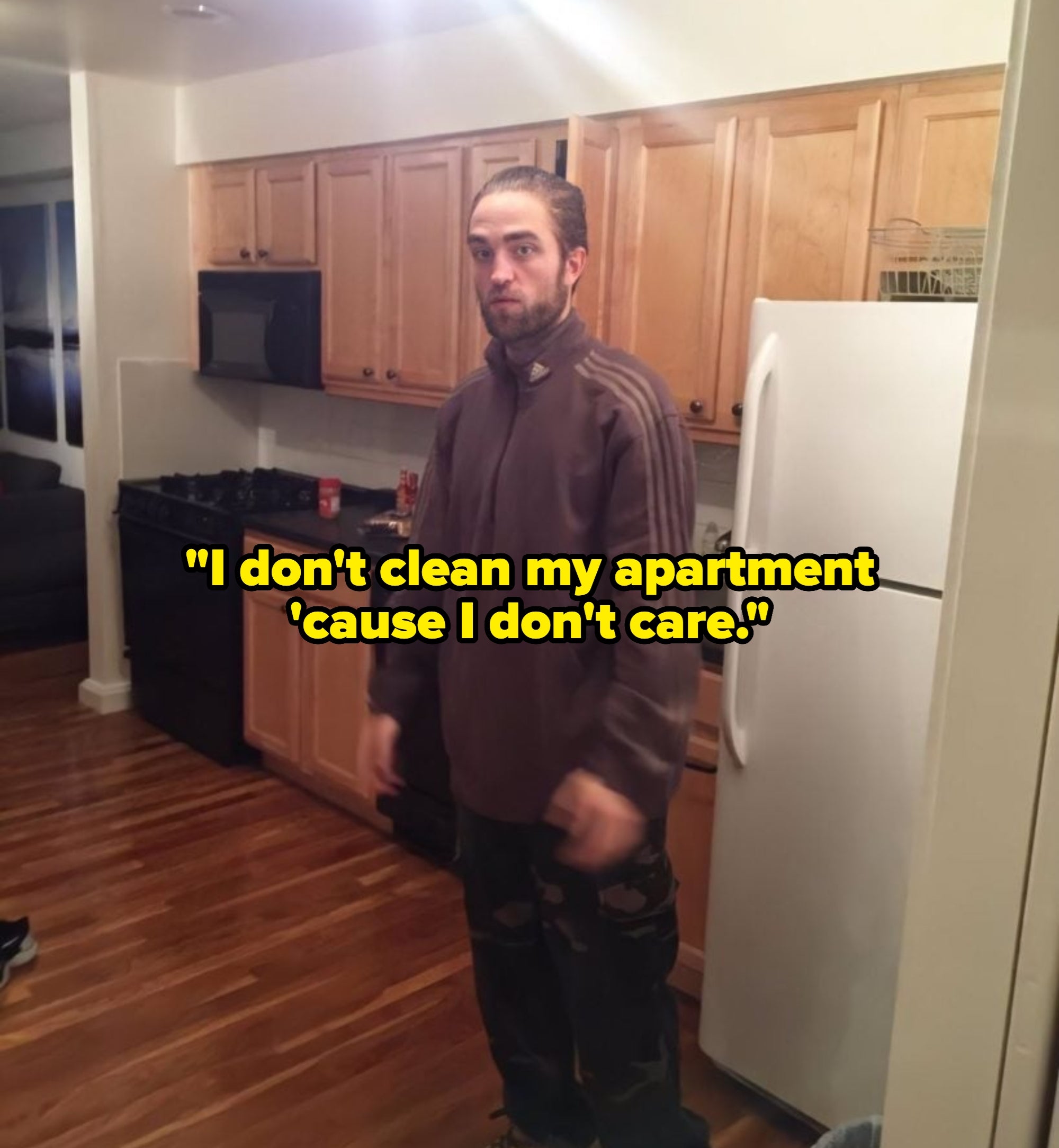 A person stands in a kitchen, wearing a long-sleeved top and jeans with boots