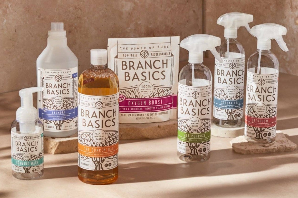 Assorted Branch Basics cleaning products are arranged on a counter in a shopping display, including bottles and sprays with plant-based formulas