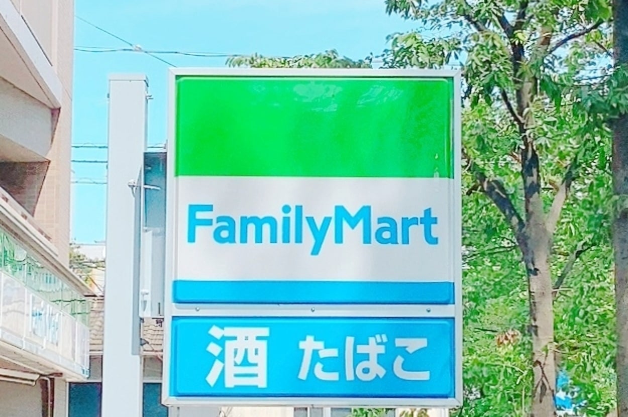 ファミリーマートの看板が街路樹のそばに立っている。下に「酒」「たばこ」の表示。