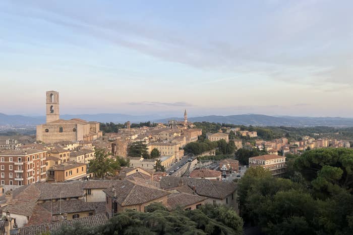 Scenic view of an Italian town with historic buildings, church towers, and distant hills under a clear sky