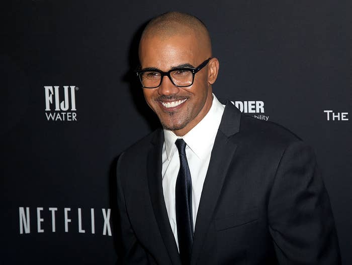 Man successful  a suit   and necktie  with glasses, smiling connected  a reddish  carpet astatine  a personage  event