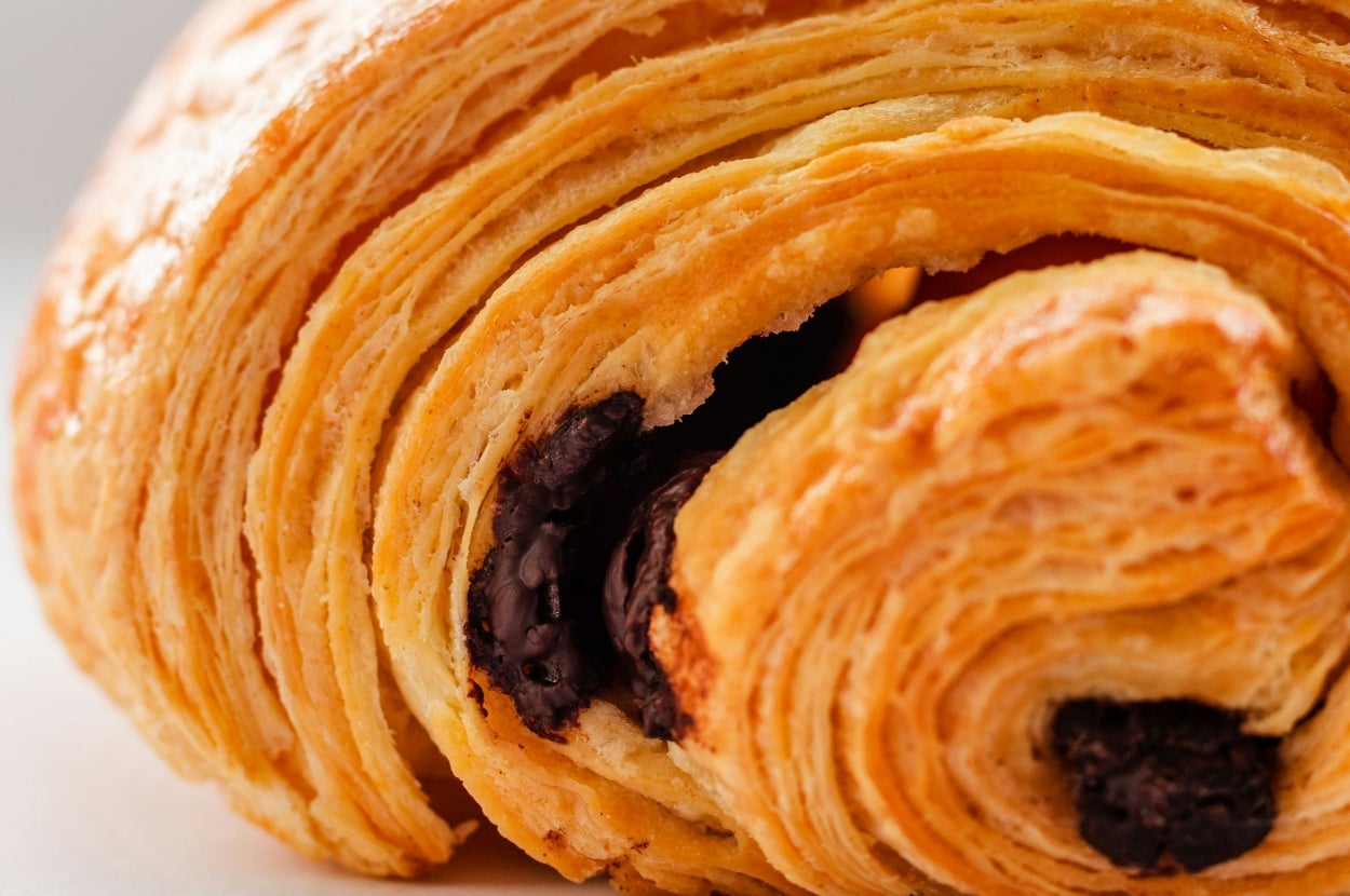 Close-up of a flaky pain au chocolat with visible layers and chocolate filling