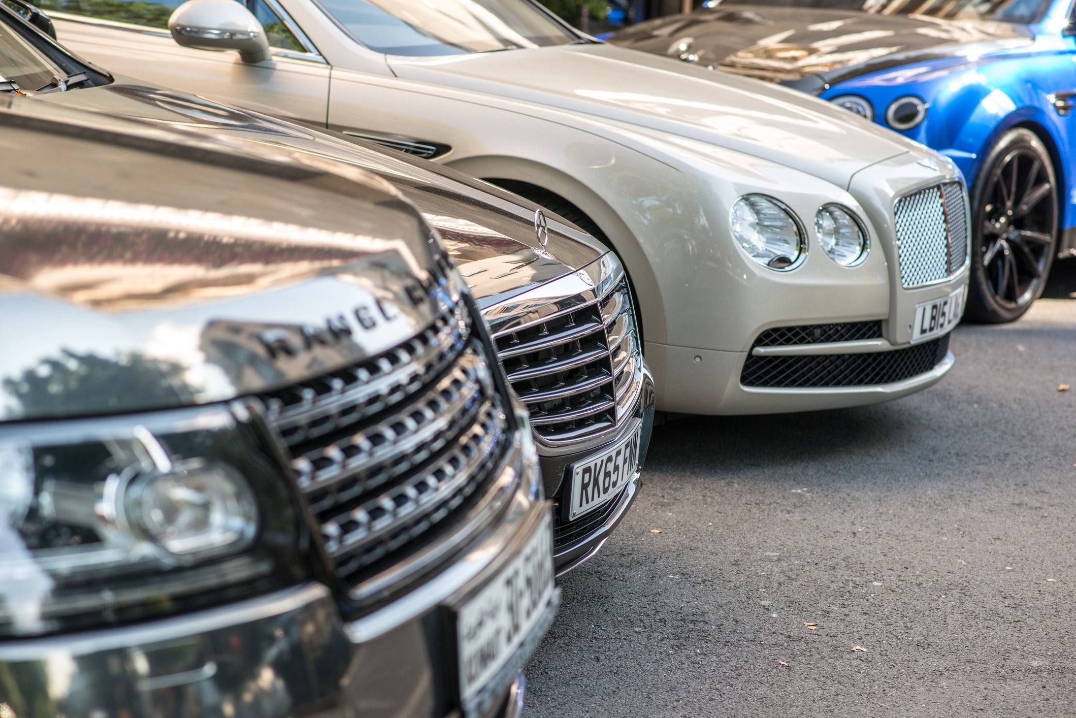 Luxury cars lined up on a street, showcasing upscale brands, illustrating wealth and status in a Work &amp;amp; Money context