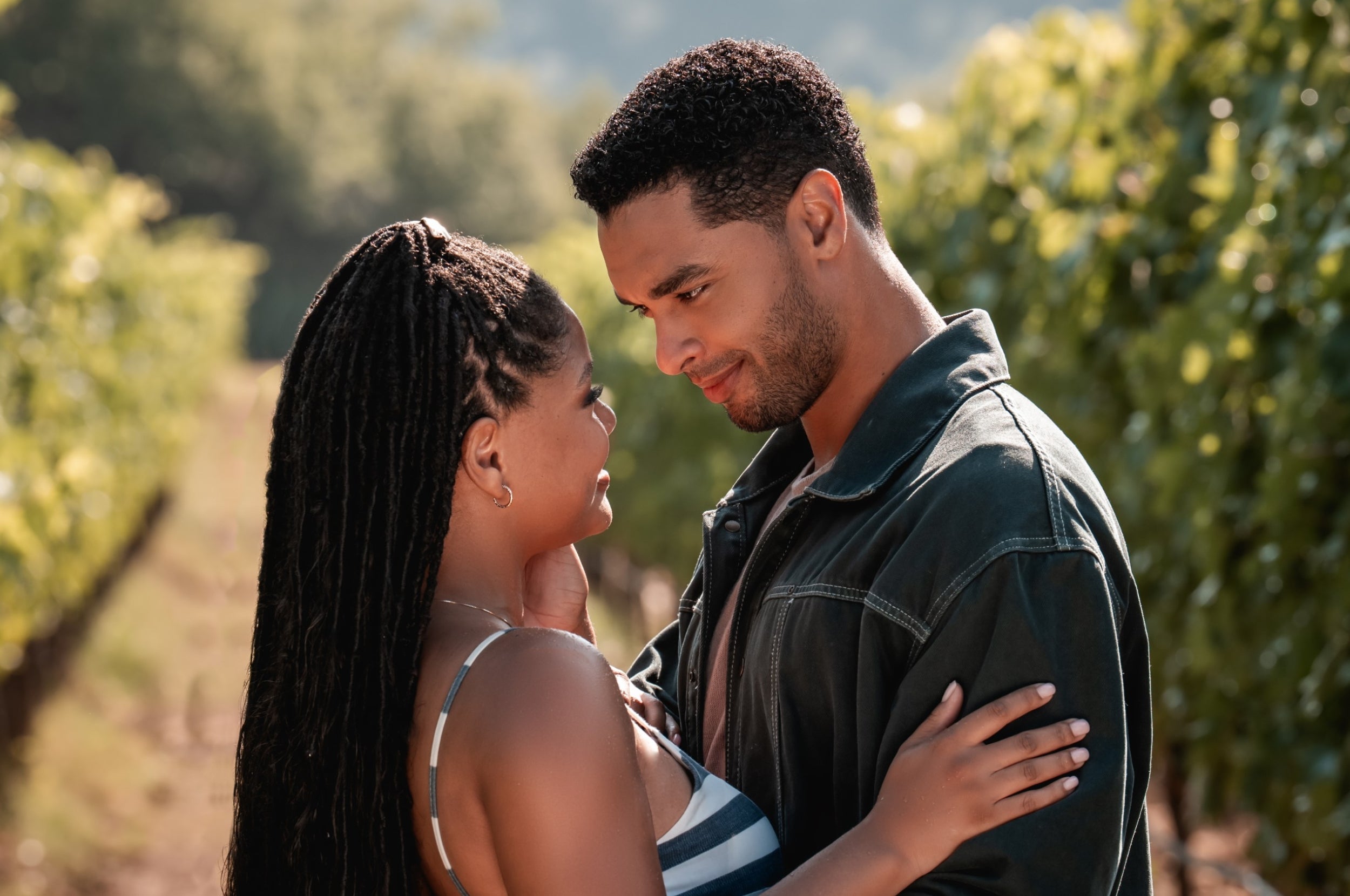 Halle Bailey and Rege-Jean Page embrace affectionately in a vineyard, exchanging tender gazes as Anna and Michael in You, Me and Tuscany