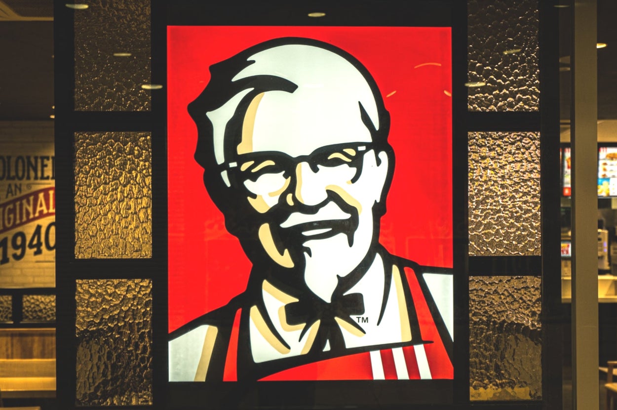 KFCのロゴマークが窓ガラスに描かれた店舗の内部。背景に店内の様子が見える。
