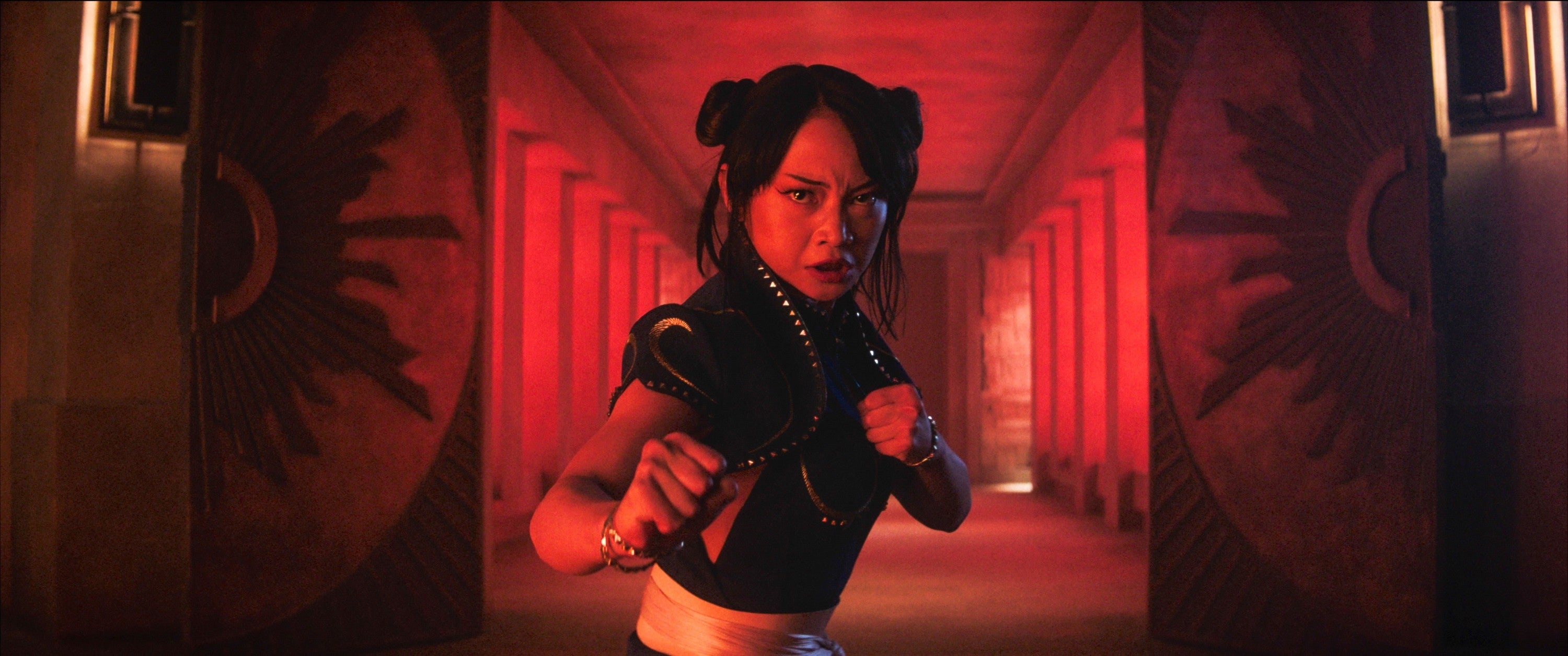 Person dressed in martial arts attire posed in an action-ready stance in a corridor with ornate doors