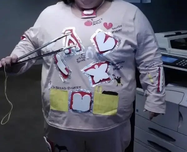 Person successful patchwork-themed outfit with reddish nose, lasting adjacent to a printer, holding tongs with a shot attached