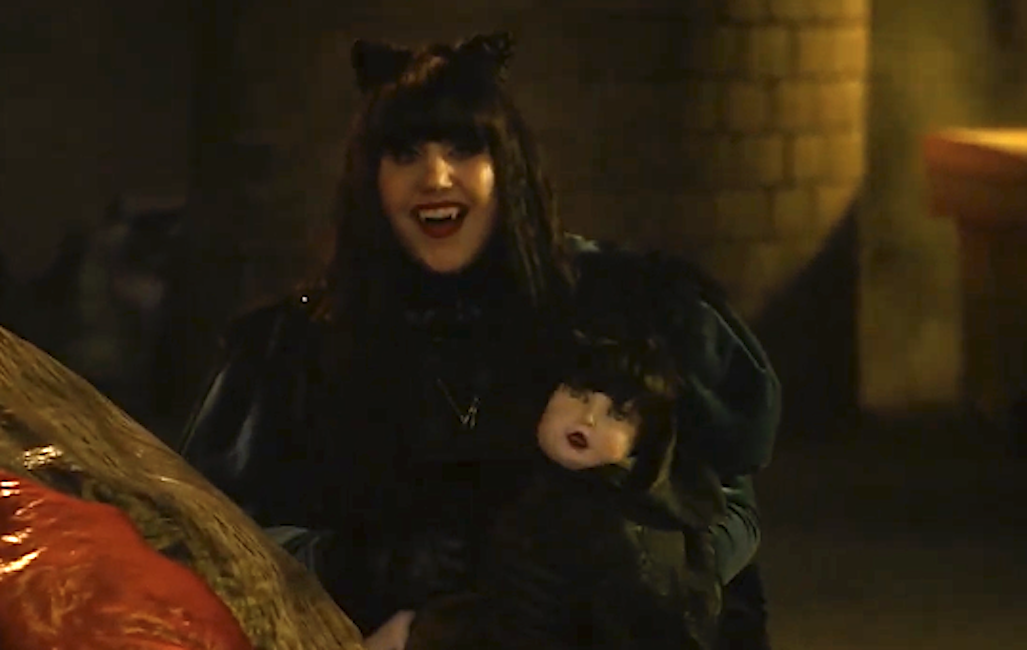 Person dressed successful dark, gothic attire with feline receptor headband, holding a doll, smiling successful a dimly lit setting