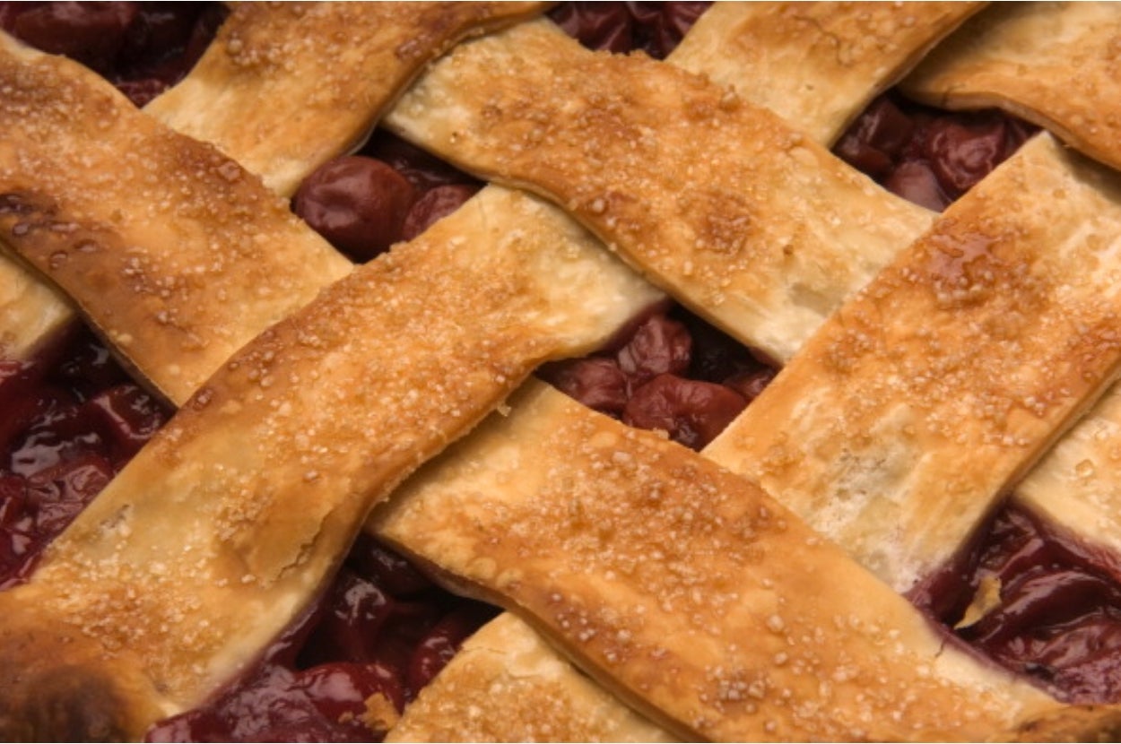 Close-up of a cherry pie with a lattice crust, showing details of the flaky pastry and cherry filling