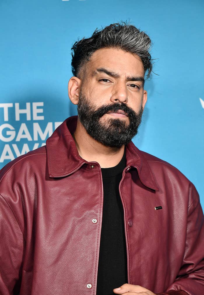 Actor Rahul Kohli  with beard and salt-and-pepper hair wearing a casual leather jacket, posing at a gaming event