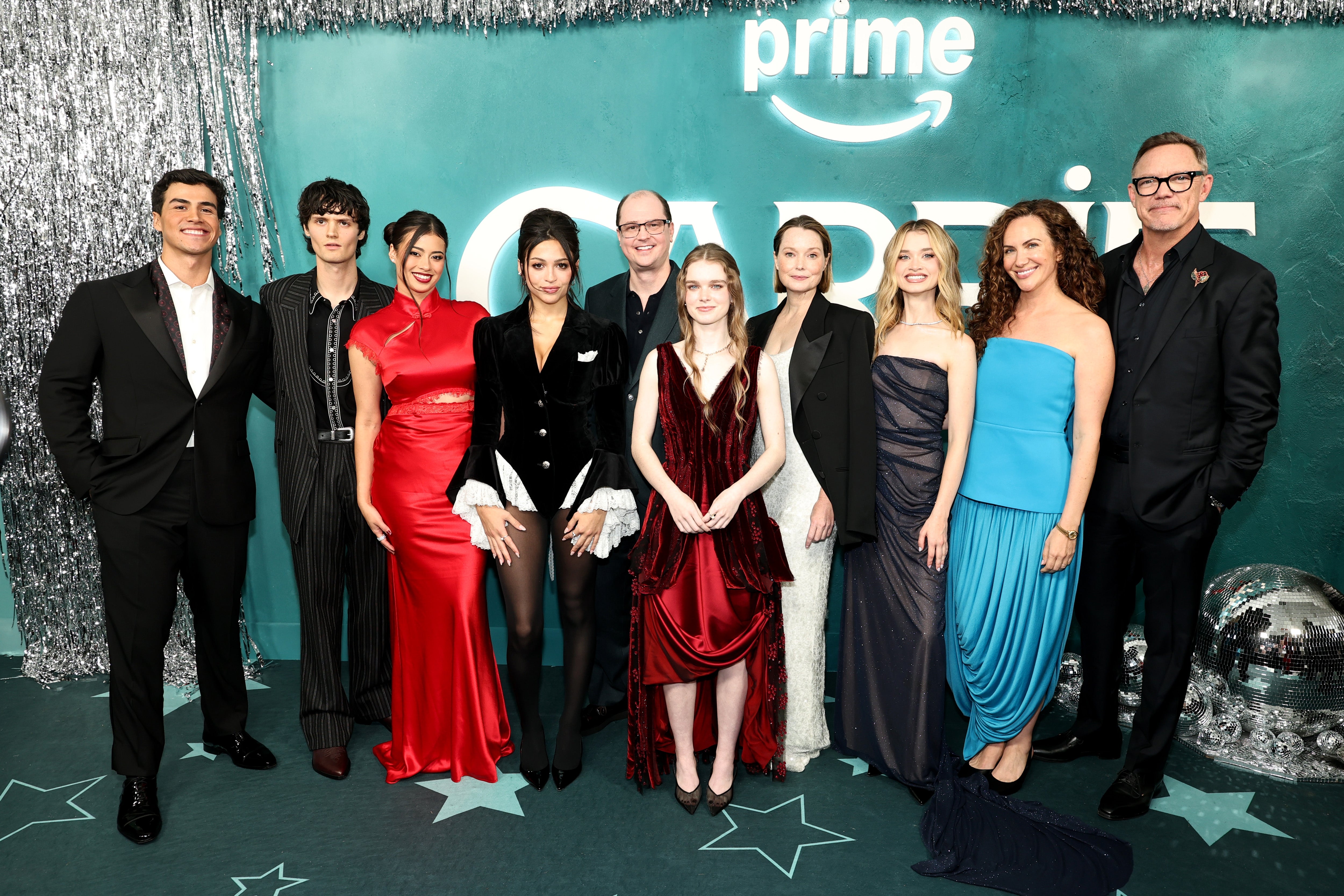 Group of actors from the new "Carrie" adaptation dressed in formal attire at a Prime Video event, standing on a decorated carpet with a backdrop