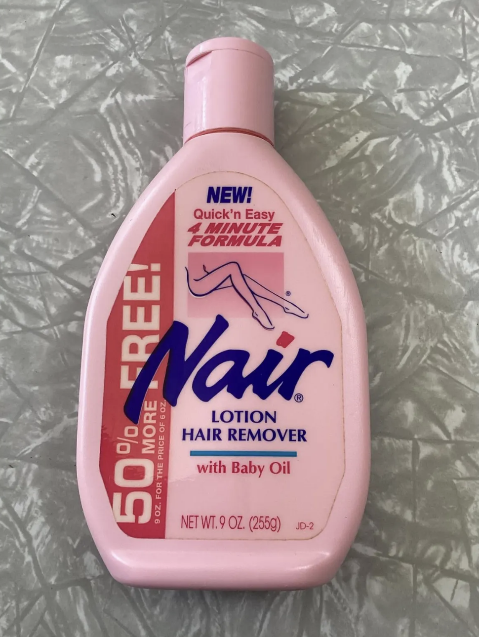 Nair lotion hair remover bottle with text on quick and easy 4-minute formula, 50% more free, and contains baby oil