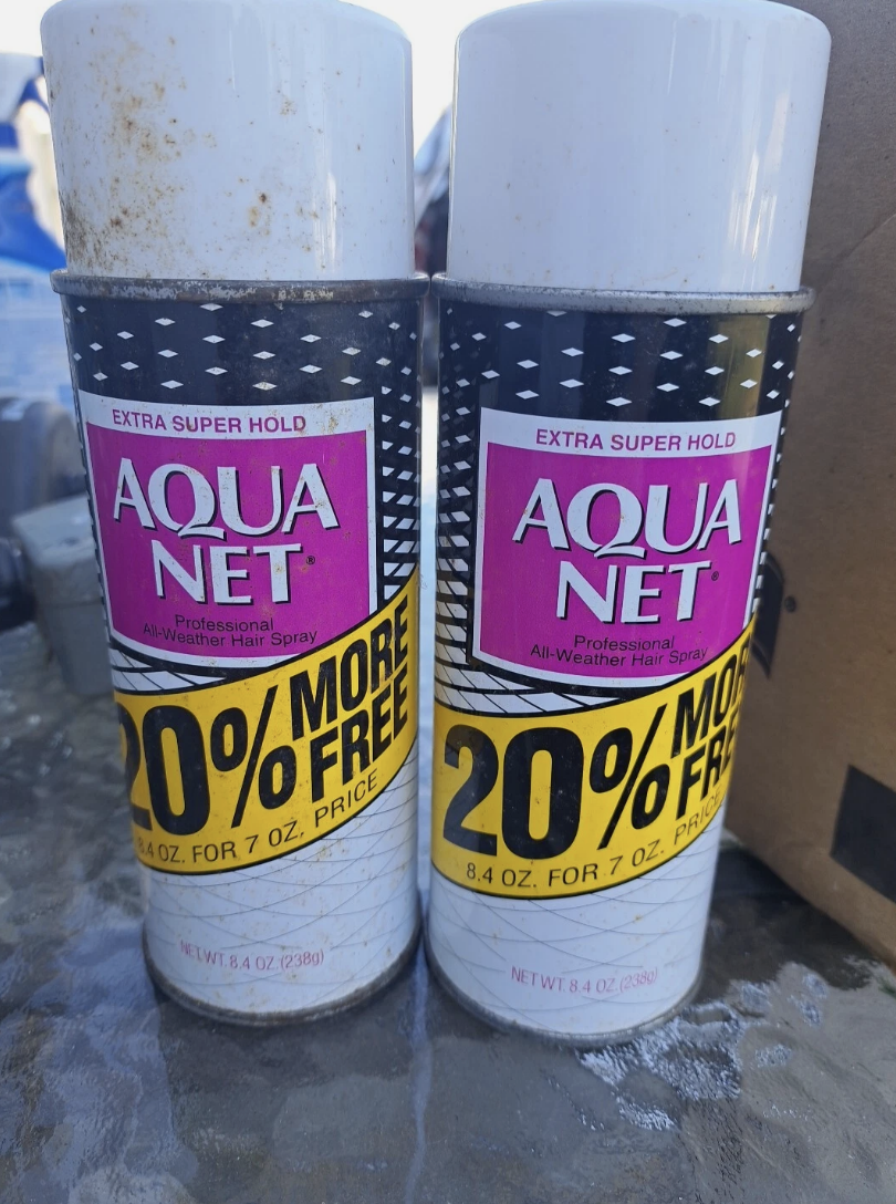 Two cans of Aqua Net hairspray featuring a promotion: "20% more free."