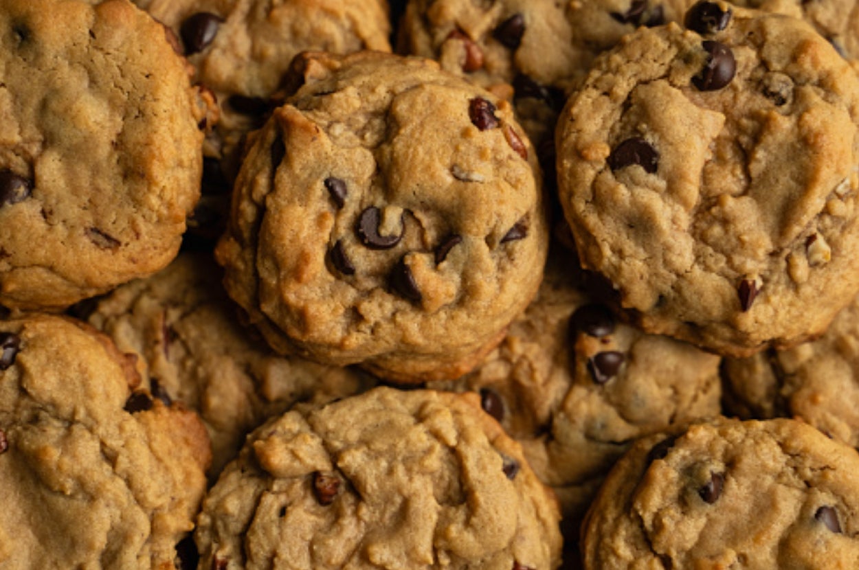 A pile of chocolate chip cookies with a slightly rough texture and visible chocolate chips